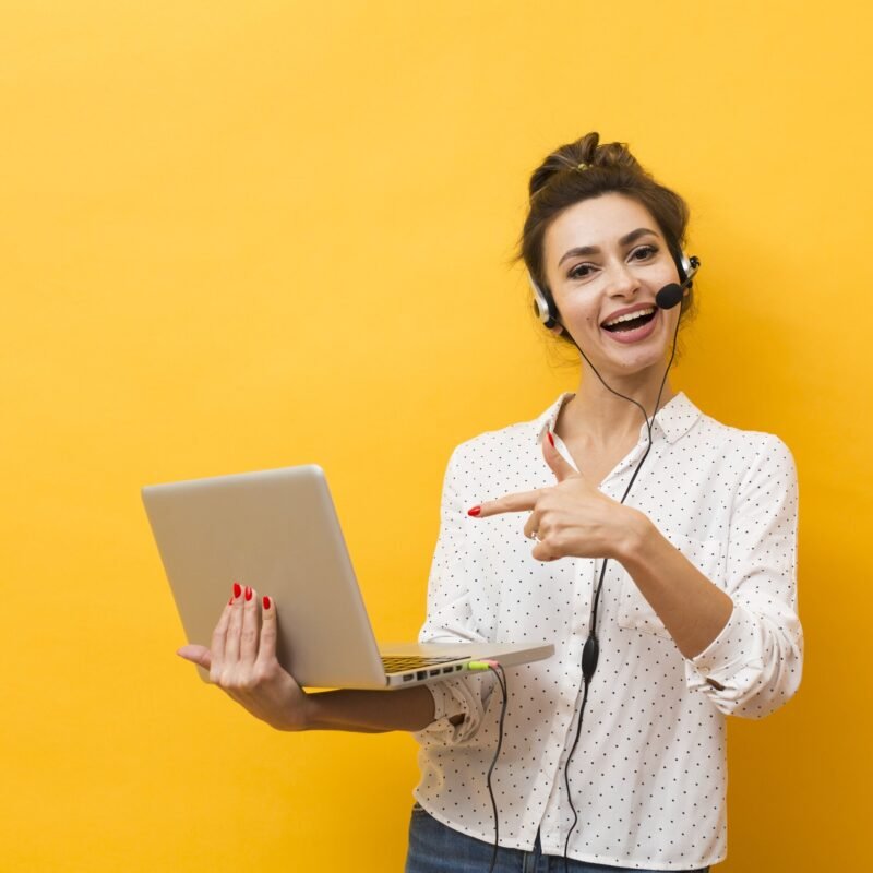 smiley woman wearing headset pointing laptop that she s holding 1 scaled