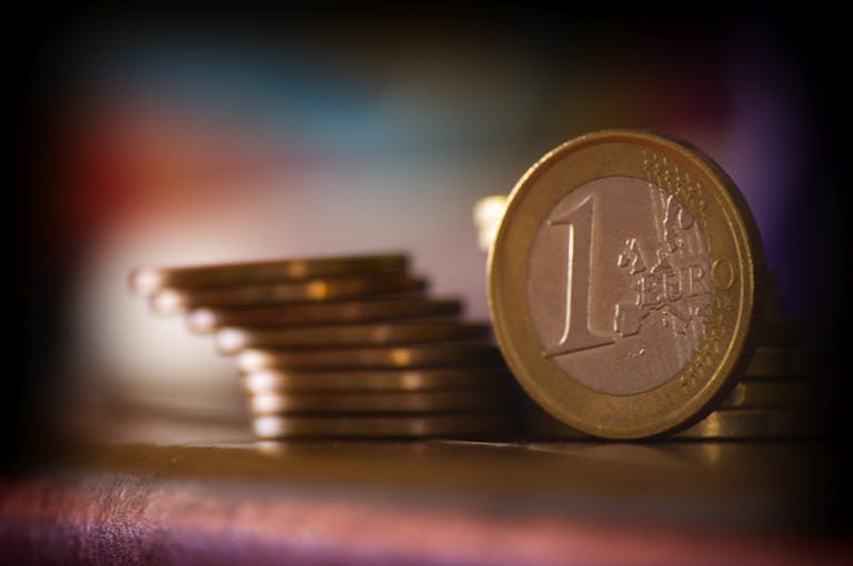 A close-up shot of stacked euro coins with a blurred colorful background, representing financial concepts.